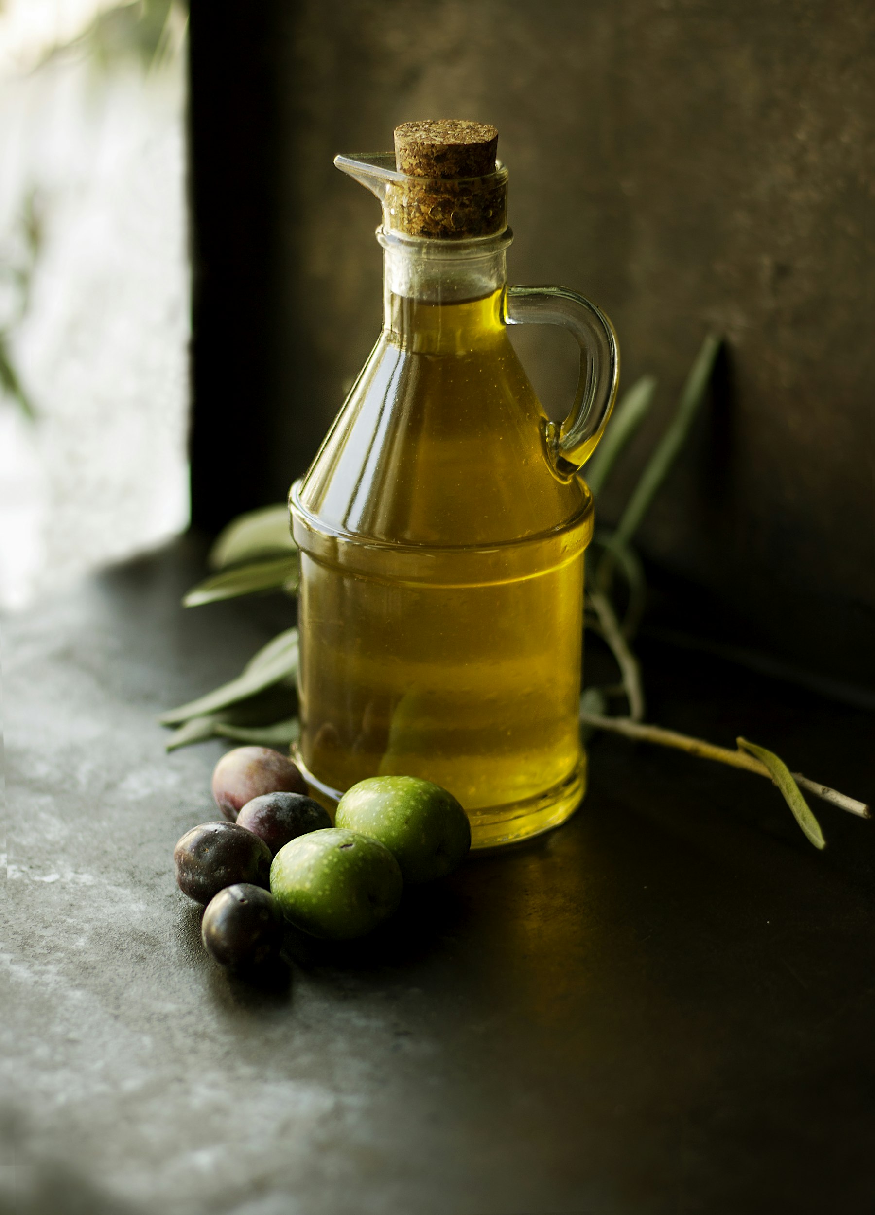 Bottle of olive oil with fresh olives